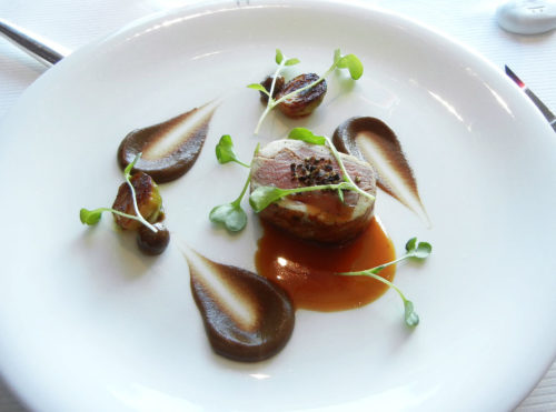 Lamb Saddle cooked in crepine perfumed with marjolaine flower, cauliflower puree and black garlic, green lentil gnocchi